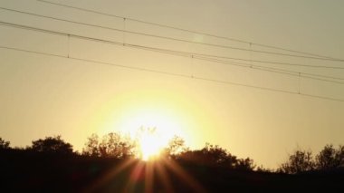 Bakım ve onarım trenleri gün batımında siluet içinde demiryoluna çıkar. Güneş ışınları parlıyor.
