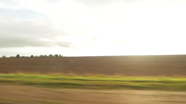 The evening sun sets against the background of a field in autumn. Movement, view from the car, background — Stock Video