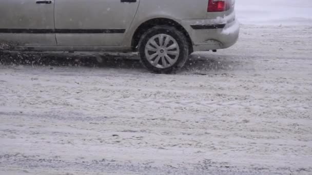 Bilen kör på en snöig väg i staden på vinterdäck. Vintertrafiksäkerhetskoncept, kopieringsutrymme, slow motion — Stockvideo