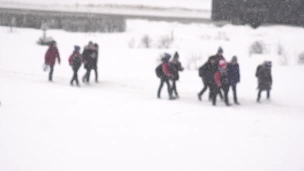 Schoolkinderen die op sneeuw lopen van school in sneeuw, achtergrond. Langzame beweging, wazig — Stockvideo