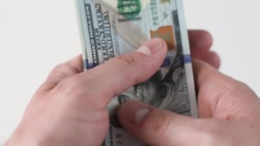 Adam 100 Amerikan Doları 'na dokunuyor ve elinde tutuyor. Nakit banknotlar halinde. Yozlaşma ve rüşvet konsepti. 100 'lük banknotların döviz değişimi. Finans, yatırım. Zengin iş ekonomisi