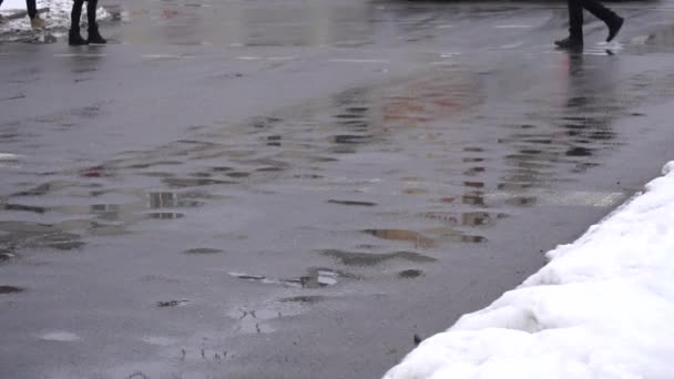 Menschen in Schuhen laufen im Winter auf nassem Asphalt. Straßenreagenzienkonzept, Kopierraum, Zeitlupe — Stockvideo