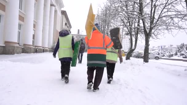 Группа уборщиков с лопатами в городе отправляется убирать снег зимой, медленно. Удаление снега — стоковое видео