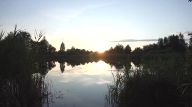 Ormandaki akşam gölüne karşı güneşli bir günbatımı. Doğada dinlenme ve rahatlama kavramı