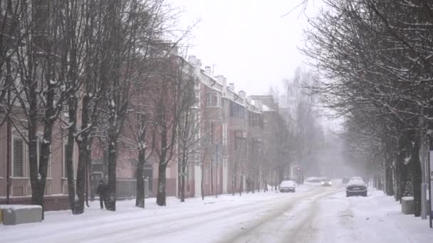 冬には市内で雪が降る。雪道、背景、スローモーションで運転する車 — ストック動画