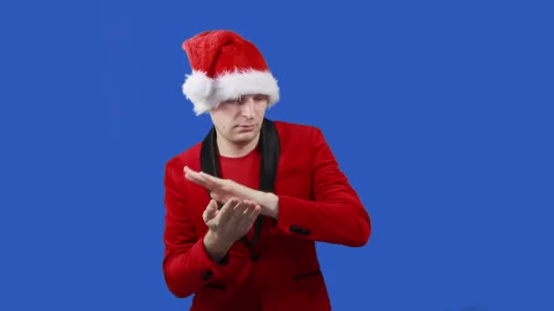 Noel Baba gibi bir adam mavi ekranda dans eder, zaman ayarlı. Noel ve Yeni Yıl konsepti. İndirim, promosyon, satış. Kırmızı elbiseli ve şapkalı adam krom anahtarın yanına yaklaşır. — Stok video