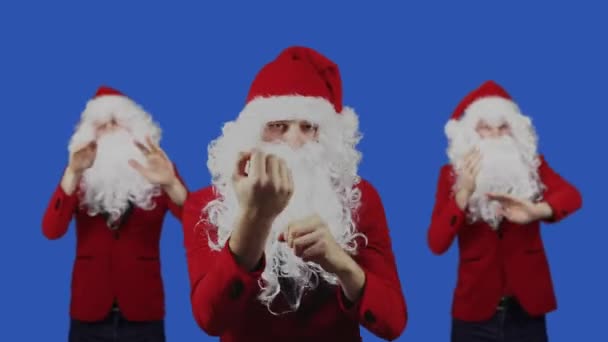 Hombres como Santa Claus bailan sobre fondo de pantalla azul. Navidad y Año Nuevo concepto. Descuentos y promociones, ventas. Tres tipos con barba blanca y sombrero rojo están en Chromakey — Vídeo de stock
