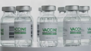 Döngülü. COVID-19 koronavirüs tedavisi için yapılan aşılar araştırma laboratuarında yavaşça döndürülmektedir. Aşı, iğne, salgın sırasında klinik deney. Şişeler, şişeler saat yönünde dönüyor. Geniş makro