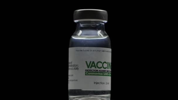 Un flaconcino di vaccino per la cura del coronavirus COVID-19 sta lentamente girando nel laboratorio di ricerca. Vaccinazione, iniezione, sperimentazione clinica durante la pandemia. Bottiglia, la fiaschetta gira in senso orario. Macro al buio — Video Stock