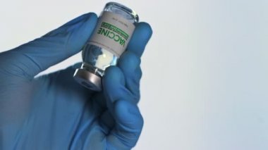 Eldivenli doktor elinde Coronavirus COVID-19 aşısı için araştırma laboratuarında bir şişe aşı tutuyor. Aşı konsepti, salgın hastalık. Makro. Şişe matarası. SARS-Cov-2. Bir doz.