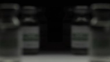 Araştırma laboratuarında COVID-19 koronavirüs tedavisi için bir şişe aşıya odaklan. Aşı, iğne, salgın sırasında klinik deney. Şişeler, şişeler karanlıkta yan taraftadır. Makro. SARS-Cov-2