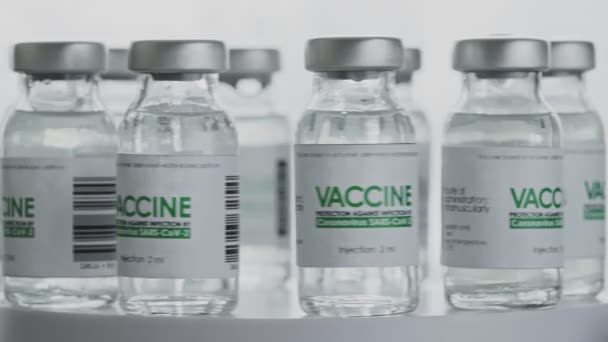 Gesloten. Flessen vaccin voor COVID-19 coronavirus genezing worden snel geroteerd in het onderzoekslaboratorium. Vaccinatie, injectie, klinisch onderzoek tijdens een pandemie. Flacons, flacons draaien tegen de klok in. Breed — Stockvideo