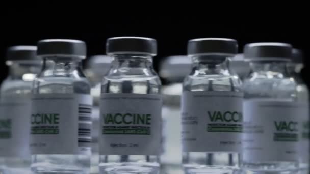 Im Forschungslabor werden schnell Impfstoffflaschen für die COVID-19 Coronavirus-Kur gedreht. Impfungen, Injektionen, klinische Studien während der Pandemie. Vials, Flaschen drehen sich im Uhrzeigersinn. Weites Makro im Dunkeln — Stockvideo