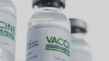 Döngülü. COVID-19 koronavirüs tedavisi için yapılan aşı şişeleri araştırma laboratuarında yavaşça döndürüldü. Aşı, iğne, salgın sırasında klinik deney. Flaconlar, şişeler saat yönünde dönüyor. Kapanış makrosu
