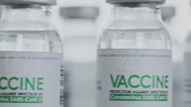 Döngülü. COVID-19 koronavirüs tedavisi için gereken aşı flakonları araştırma laboratuarında hızla döndürülmektedir. Aşı, iğne, salgın sırasında klinik deney. Şişe saat yönünde dönüyor. Kapanış makrosu