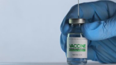 Doktor enjeksiyondan önce Coronavirus COVID-19 aşısı için aşı şişesinden şırınga dolduruyor. Aşı konsepti salgını. İğne üst kapağı delip şişenin içine giriyor. Tıbbi eldivenler. Makro geniş çekim