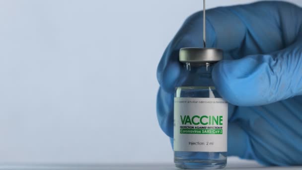 De arts vult de injectiespuit van de kolf met vaccin tegen het coronavirus COVID-19 vóór injectie. Vaccinatie concept pandemie. Naald doorboort de bovenste dop en komt in de injectieflacon. Medische handschoenen. Macro wijd schot — Stockvideo