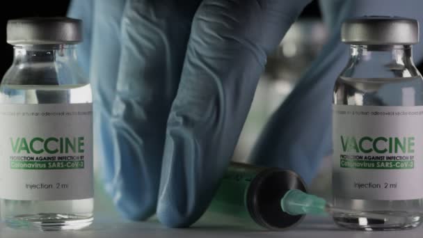 Médicos mão leva seringa para injeção de frasco para injetáveis de vacina para a cura do coronavírus COVID-19 em laboratório de pesquisa. pandemia do conceito de vacinação. Macro, luva médica protectora. Frascos, frascos, SARS-Cov-2 — Vídeo de Stock