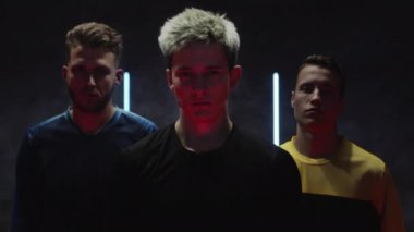 Genç beyaz erkek sporcular karanlık bir stüdyoda parlak ışıklara karşı poz veriyorlar. Futbol takımı. Futbolcu amatörler. Ağır çekimde portre. Spor. ProRes 'de Kara Büyü' yü çektik. Bahis