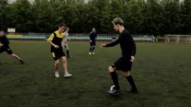 Futbolcu saldırır, top sürme numarası yapar ve takım arkadaşına pas verir. Beklenmedik futbol manevrası, aldatıcı hareket. Küçük stadyumda amatör bir maç. Egzersiz eğitimi. Takım maçı. Spor.
