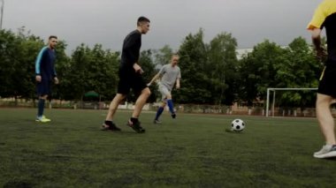 Futbolcular pas veriyor ve defans oyuncusu topu alıyor. Küçük bir stadyumda futbol amatör maçı. Egzersiz eğitimi. Takım arkadaşlığı maçı. Spor.
