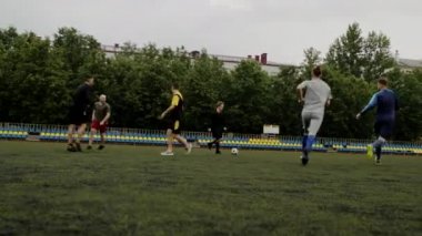 Erkekler futbol oynar ve birbirlerine pas verirler. Küçük bir stadyumda futbol amatör maçı. Egzersiz eğitimi. Takım arkadaşlığı maçı. Spor.
