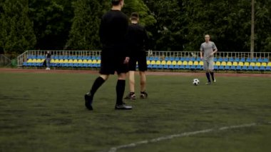 Arkadaşlar futbol oynar ve birbirlerine pas verirler. Küçük bir stadyumda futbol amatör maçı. Egzersiz eğitimi. Takım arkadaşlığı maçı. Spor.