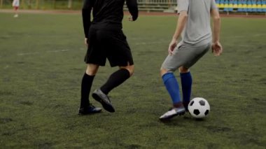 Futbolcu defansın bacakları arasında top sürme numarası yapıyor. Beklenmedik futbol manevrası, aldatıcı hareket. Küçük bir stadyumda amatör bir maç. Egzersiz eğitimi. Takım arkadaşlığı maçı. Spor.