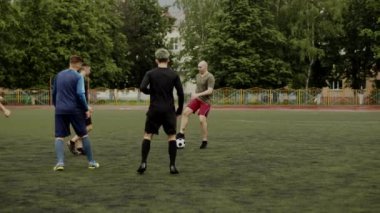 Arkadaşlar futbol oynar ve birbirlerine pas verirler. Küçük bir stadyumda futbol amatör maçı. Egzersiz eğitimi. Takım arkadaşlığı maçı. Spor.