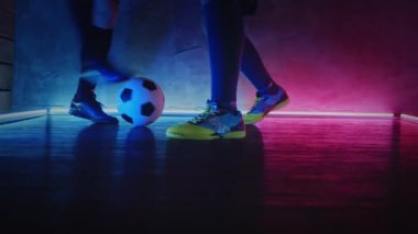 2 futbolcu antrenman yapıyor ve top oynuyor. Futbol antrenmanı konsepti. Lacivert ışıklı, koyu renkli stüdyoda top oynayan sporcular. Spor. Blackmagic ProRes 'da çekildi. Bahis
