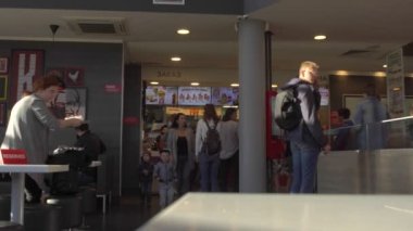 İnsanlar MINSK, BELARUS 9.7.20 'de Coronavirus COVID-19 salgını sırasında KFC restoranında fast food yiyorlar. Koruyucu maskesi olmayan ziyaretçiler çıkış yakınında sipariş veriyorlar. Rezervasyon masasının üzerinde.