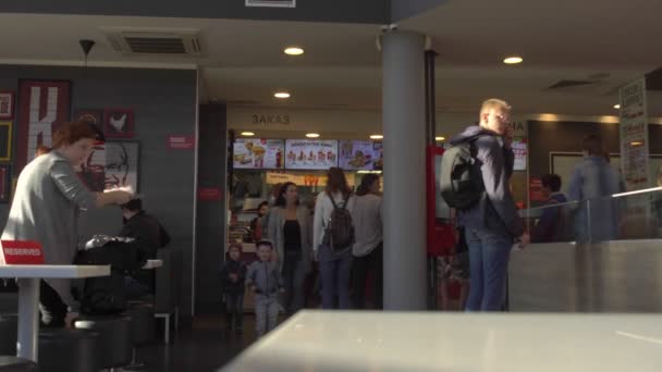 Le persone mangiano fast food all'interno del ristorante KFC durante la pandemia di coronavirus COVID-19 in MINSK, BELARUS 9.7.20. I visitatori senza maschere protettive fanno ordine vicino alla cassa. segno Riservato è sul tavolo — Video Stock