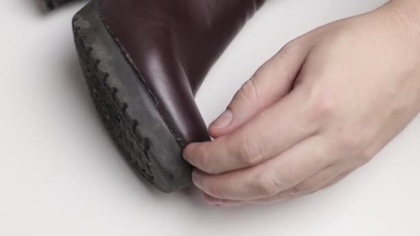 Um reparador de sapatos cola a sola de uma bota de inverno feminina. Conceito de sapatos de baixa qualidade, reparação de botas, close-up — Vídeo de Stock