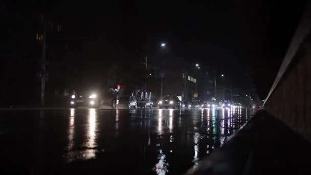 Bytrafikk i regnvær. Frontlysene reflekteres på den våte asfalten i byen. Tidsforfall – stockvideo