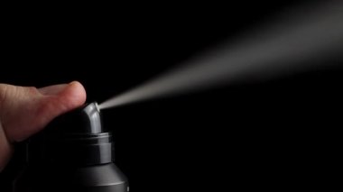 Siyah arka planda bir deodorant spreyi sıkıyor. Saç spreyi konsepti, sprey jet, makro