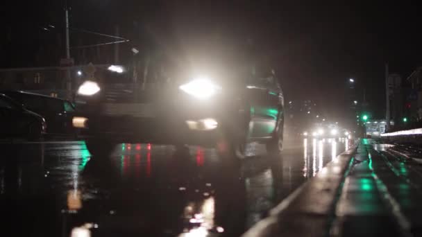 Gece şehrindeki arabaların akışı ve ıslak yoldaki farların yansıması. Yağmurlu havada, trafikte, arka planda görüş mesafesi zayıf — Stok video