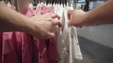 Marketten şık kıyafetler seçip, malzemelerin kalitesini kontrol etmek. Gömlekler ve tişörtler için alışveriş konsepti, ceketler, arka plan