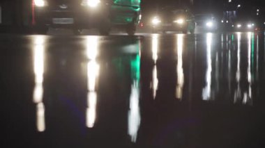 Gece şehrindeki arabaların akışı ve ıslak yoldaki farların yansıması. Yağmurlu havada, trafikte, arka planda görüş mesafesi zayıf