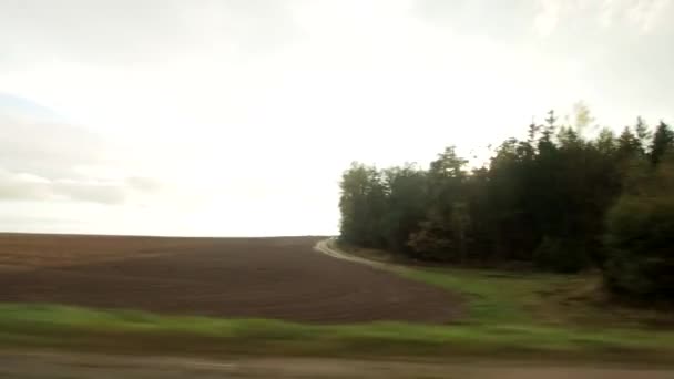 Zicht vanuit het autoraam op een reis. Zonsondergang van achter het bos op een veld in de herfst, kopieer ruimte, landschap — Stockvideo