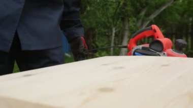 Bir adam elektrikli bir uçakla ahşap bir yüzeyi işliyor, yakın plan. Ahşap ürünler, el yapımı, elektrikli aletler