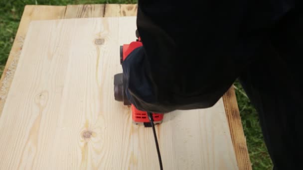 En man bearbetar en träyta med ett elektriskt plan, närbild. Handgjorda trävaror, elektriska verktyg — Stockvideo