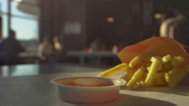 Fast food restorandaki kafede, erkek el kaldırır ve patates kızartmasını sos ketçapına batırır. Patates. Sağlıksız yaşam tarzı, yüksek kalorili zararlı fast food.