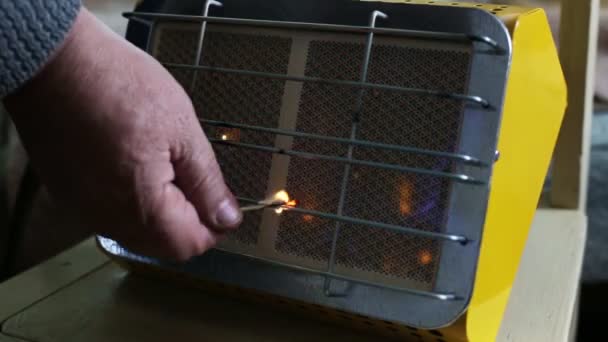 Un homme met le feu à un appareil de chauffage en céramique pour sa maison avec une allumette, qui est alimenté par le gaz. Gros plan, industriel — Video