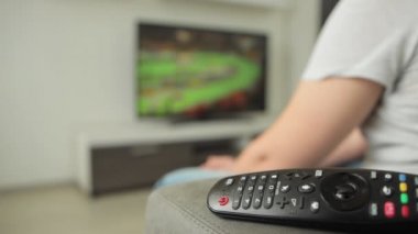 Hayranlar evdeki kanepede oturur ve TV 'de spor müsabakalarını izler. Yaz olimpiyat oyunları yarışması. Atletizm 2021 'de. Adam modern iç dairede plazma yayını izliyor. Tokyo