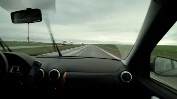 Θέα από το παρμπρίζ ενός αυτοκινήτου κατά την οδήγηση σε αυτοκινητόδρομο με νεφελώδη βροχερό καιρό. Ταξιδιωτική έννοια, φόντο — Αρχείο Βίντεο