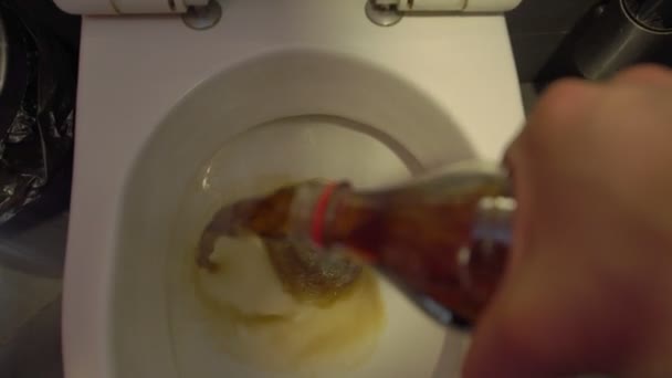 Man pours the beverage carbonated soft drink down from a bottle into flush toilet bowl WC. Healthy food concept. Avoiding rejection high-calorie drinks. Aggressive advertising campaign of competitor — Stock Video