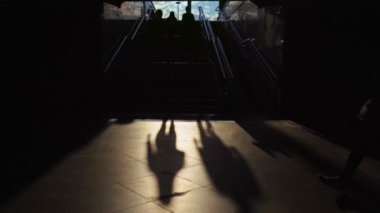 İnsanlar Susnet 'teki merdivenlerin yakınındaki karanlık alt geçitten geçerler. Yeraltı geçidi, metro. Siluet. Metroya giden koridor. Seyahat ve şehir hayatı kavramı, soyut