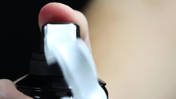 The mans hand presses the canister and squeezes out the shaving foam. Black background, macro — Stock Video