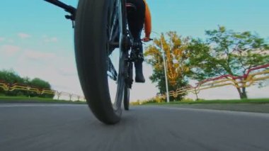Adam şehir dışında MTB bisikleti sürüyor. Tekerlek yakın çekim. Zincirleme sürüş, arka raydan çıkarıcı ve kaset. Dağ bisikletinin vitesi. Jokey tekerlekleri, aylak aylak aşağı ve yukarı makaralı. Cogset dişlileri. Vites değiştir.