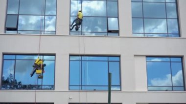 Cam temizleyiciler binanın dışında çalışıyor. Güvenlik halatıyla profesyonel cephe işi. Temizlik servisi. Erkek aşırı iş için tehlikeli bir risk. Dağcı adamlar. Güvenlik.